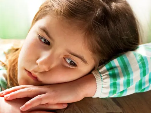 Smutna dziewczynka, 9 latek nie radzi sobie z emocjami, opiera głowę na ramieniu.
