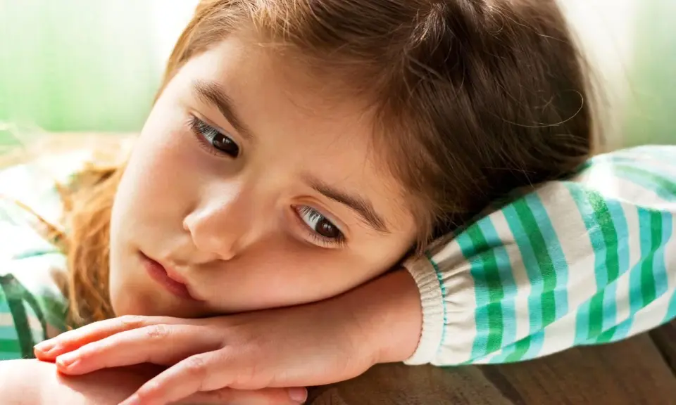 Smutna dziewczynka, 9 latek nie radzi sobie z emocjami, opiera głowę na ramieniu.