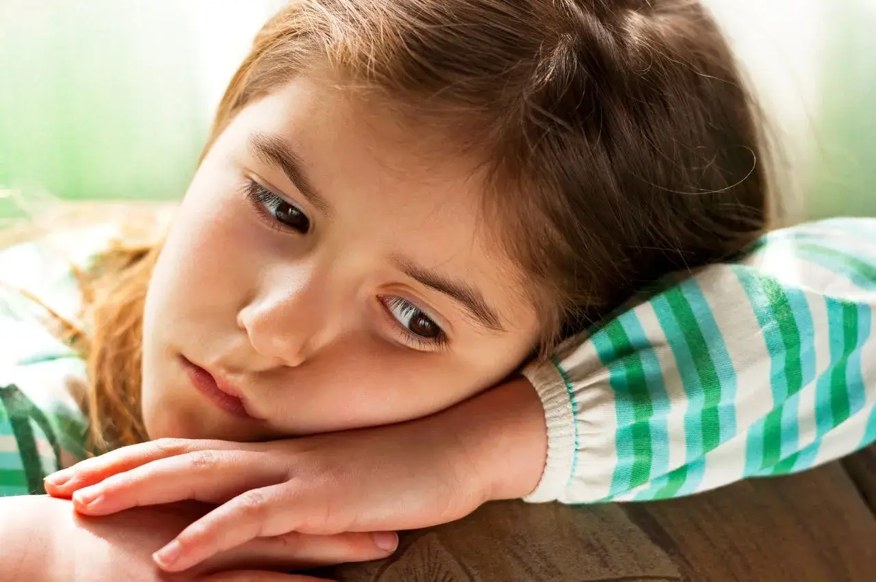 Smutna dziewczynka, 9 latek nie radzi sobie z emocjami, opiera głowę na ramieniu.